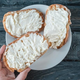 Hand reaching for toast with cream cheese on plate